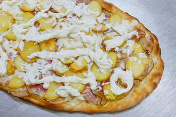Pizza con patate al forno, porchetta e burrata pugliese appena sfornata e poggiata su un piano da...