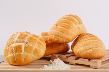 Panini appena sfornati di diverse dimensioni fotografati su un tagliere di legno e con una montagnetta di farina davanti