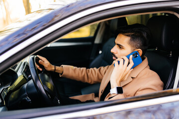 Indian Businessman talking on cell phone while driving and overtaking, not paying attention to the road and traffic