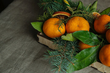 Fresh tangerines, Christmas tree twigs and lollipop in wooden box. Christmas table decoration. Festive food background.