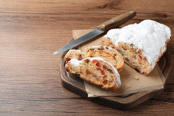 Traditional Christmas Stollen with icing sugar on wooden table, space for text