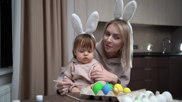 Mother and daughter paint Easter eggs. Happy family is preparing for Easter. make a video call and communicate via video communication.