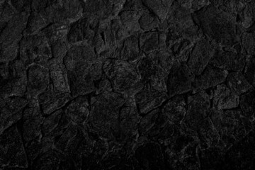 Many black stones arranged in layers looks mysterious. It may be a cave wall, used as a background, suitable for institutions and karma and design work, or suitable for geological work.