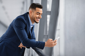 Handsome Young Arab Businessman Using Smartphone In Airport While Waiting In Lounge