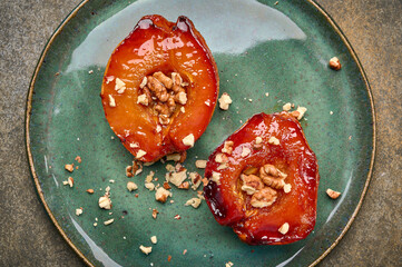 Close up homemade baked quince with honey, walnut and cinnamon on green plate on rustic background. Flat lay. Healthy vegetarian dessert
