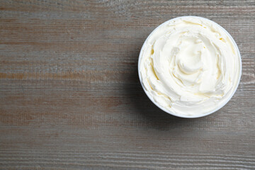 Bowl of tasty cream cheese on wooden table, top view. Space for text