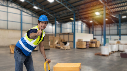 Warehouse worker pulling a pallet truck and taking or upload package box to shelf in large warehouse. Active caucasian man showing thump up and looking at camera with smiling.