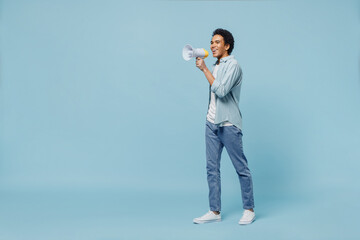 Fototapeta na wymiar Full size body length side view young black curly man 20s wears white shirt hold scream in megaphone announces discounts sale Hurry up isolated on plain pastel light blue background studio portrait.