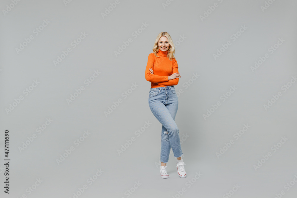 Wall mural full body elderly smiling happy blonde caucasian woman 50s in orange turtleneck hold hands crossed f