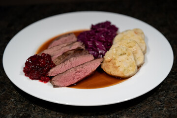 delicious meal from a young chamois with napkin dumplings and red cabbage, brown sauce and cranberries