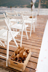 Fototapeta na wymiar Box with twisted envelopes with flower petals stands next to a row of white chairs