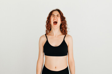 Obraz premium Happy cute redhead woman with curly hair with closed eyes and open mouth, making silly face over white background. Overwhelming emotions