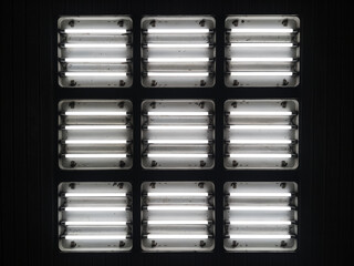 Nine square lampshades with four fluorescent lamps on the ceiling.