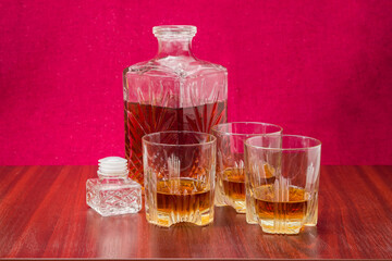 Whisky in three glasses and decanter on a wooden table