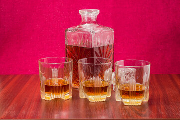 Whisky in three glasses and decanter on a wooden table