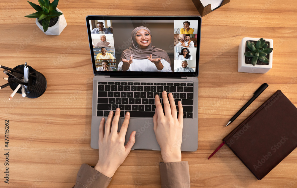 Poster lady having group videoconference on laptop while working at desk in office