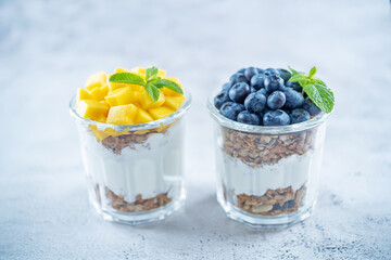 Mango  and blueberry Greek yogurt granola parfait in a glass