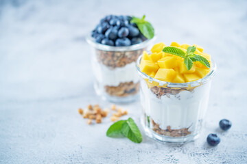 Mango  and blueberry Greek yogurt granola parfait in a glass