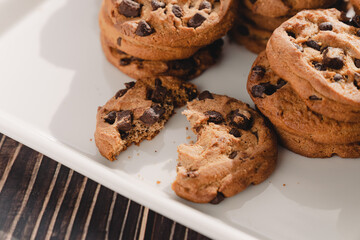 A lot of chocolate chip cookies on a white plate.