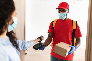 Black man holding POS machine lady paying with smart watch