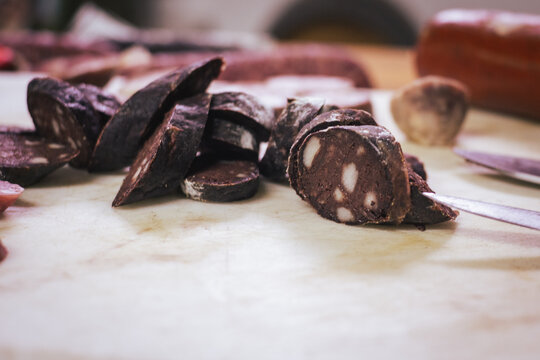 Tapa de morcilla cortada sobre una tabla y de fondo m&aacute;s embutidos t&iacute;picos de la gastronom&iacute;a espa&ntilde;ola que se suelen tomar en Navidades 