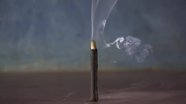 Slow burning incense stick emits smoke. Isolated.