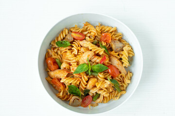 Close up Tasty Gourmet Spicy Pasta with Tomato and Herbs on a White Plate, Served on Top of a white wooden  Table.