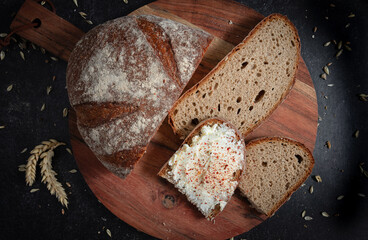 Sliced homemade bread on a wooden board with butter and seasoning.