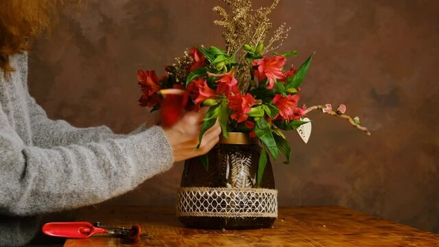 Valentines day flower arrangement, festive home decor. Florist makes bouquet of red flowers for Valentine's day. Florist at work.