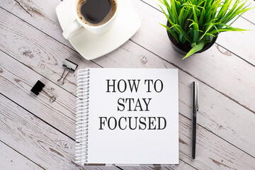 Cofee cup, notepad,pen on the wooden background. Business concept. Text HOW TO STAY FOCUSED