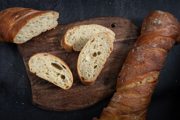 Half sliced ciabatta on dark rustic wood. dark background. Top view.