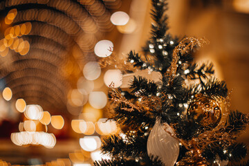 Golden shiny magic Christmas ball and decor hanging on the Christmas tree. Winter holiday fairy garlands illumination and festive details in the interior © asauriet