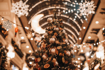 Creative unusual Christmas tree decorated with dried oranges, mandarins, pine cones and golden shiny Christmas balls. Magic details. Winter holiday season in festive interior