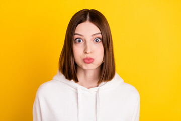 Photo of childish crazy lady inflate cheeks hold breath wear white sweatshirt isolated yellow color...