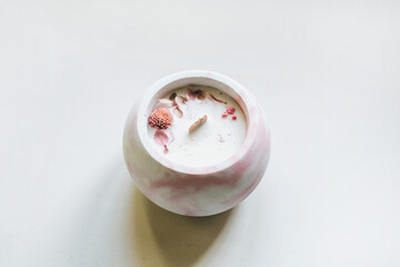 Ecological and vegan handmade candle on a white background with dry flowers in a glass made of concrete. Soy or coconut candle with a wooden wick..