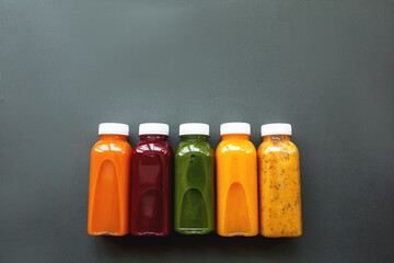 Fresh juices or cocktails of fruits and vegetables in bottles on a gray background. The concept of a healthy diet or diet