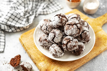 Homemade chocolate and coffee crinkle cookies in a white plate on the kitchen table. Traditional American cookies for Christmas with cracks and powdered sugar on a culinary background 