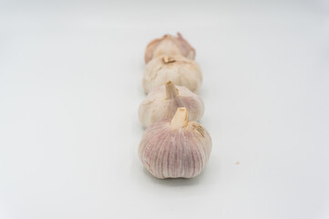 Ripe garlic in a straight line.Some garlic heads photographed against a white background. Still life shot. Purple and white garlic heads.