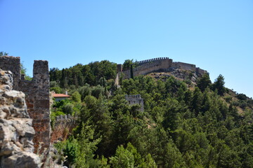 Fototapeta na wymiar ancient fortress on top of mountain among green trees, Alanya