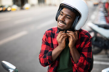 African man with scooter in the city. Young man riding a scooter...