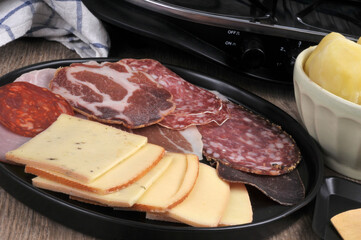 Assortiment de charcuterie et tranches de fromage pour faire une raclette