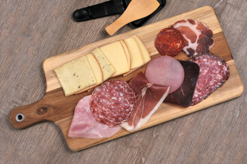 Assortiment de charcuterie pour faire une raclette sur une planche à découper