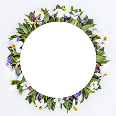 Round frame with spring flowers. Mint, violets and dunes in the form of a wreath on a white wooden background.