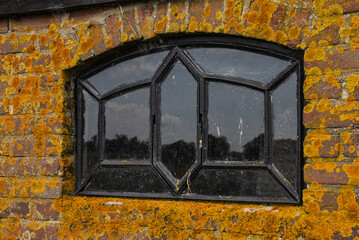 Texel, the Netherlands - October 2021. Old window in a mossy wall.