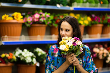 Smiling woman holding a bucket of flowers in a florist shop