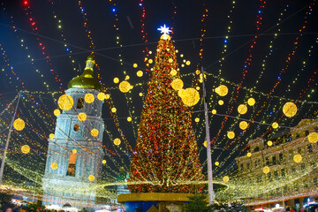 Christmas tree with bright festive illuminations and St. Sophia bell tower at the Sofiyska square in Kyiv, Ukraine