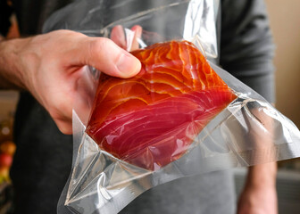 A man holding a red fish in a package