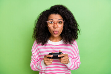 Portrait of attractive cheery funny amazed addicted girl playing console pout lips isolated over bright green color background