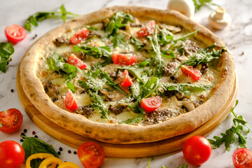 Appetizing, fresh pizza is on the table. Food from an Italian restaurant. Cooking pizza. Pizza ingredients.
