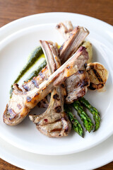 Roasted beef ribs on bone on white plate on wooden background.